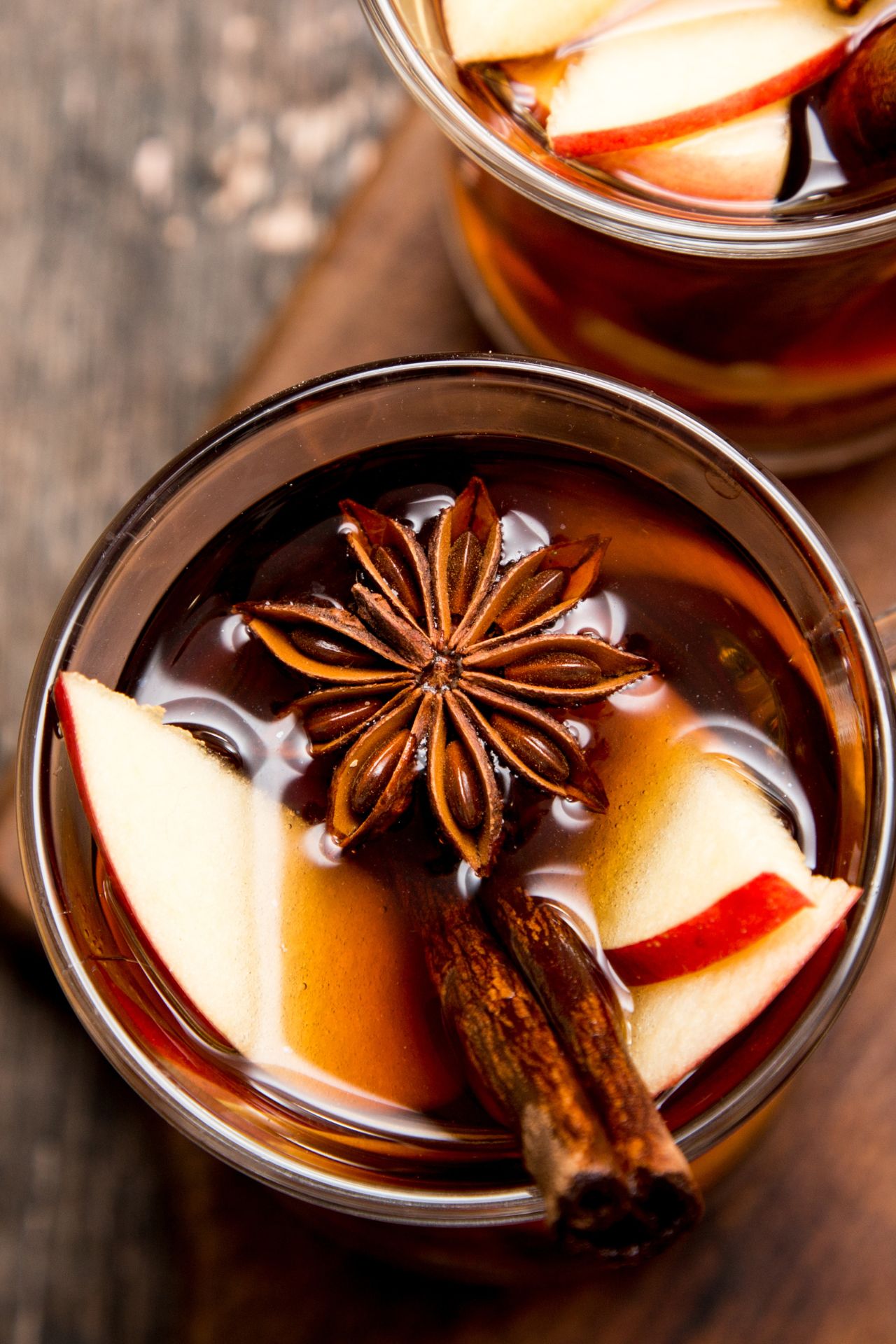 Nahaufnahme einer Tasse Glühwein mit Apfelscheiben, Zimtstange und Sternanis