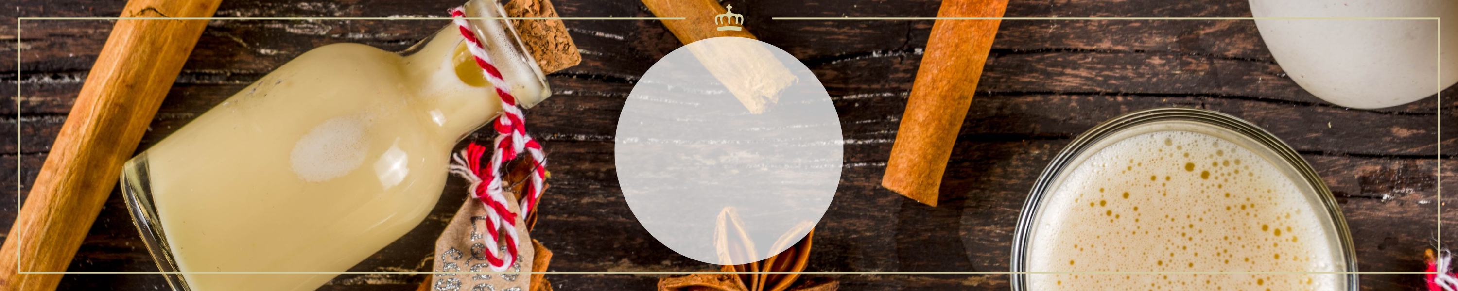 Flasche Eierlikör mit Zimtstangen und Gewürzen auf rustikalem Holztisch