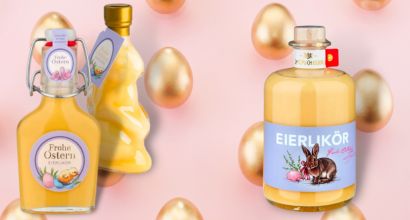 Drei Flaschen Eierlikör mit Osterdekoration vor einem rosafarbenen Hintergrund mit goldenen Eiern