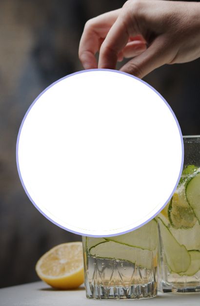 Hand drapiert Gurkenscheiben in ein Glas mit Zitrone und Eis