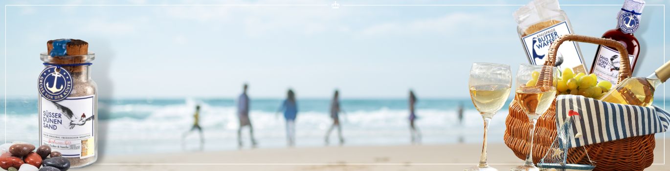 Ein Strand-Picknick mit einem Korb voller Wein, Trauben und maritimen Leckereien, neben einem Glas mit süßem Dünen-Sand.