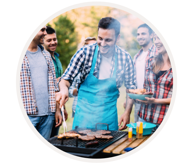 Eine Gruppe von Freunden genießt eine Grillparty im Freien, ein Mann wendet das Fleisch auf dem Grill.