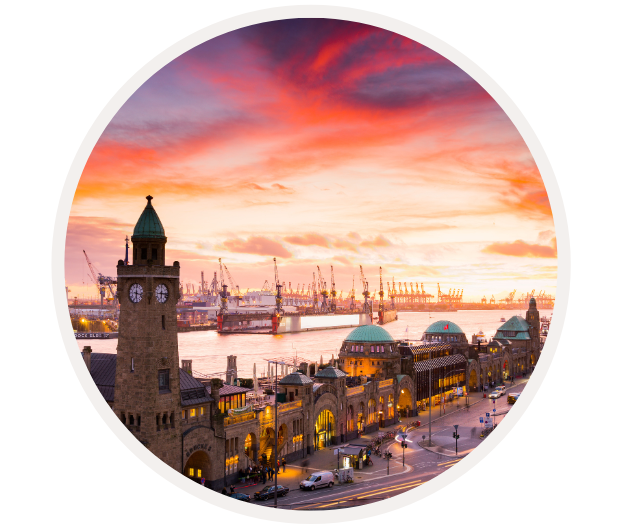 Blick auf die Landungsbrücken in Hamburg bei Sonnenuntergang mit Hafen und Schiffen im Hintergrund