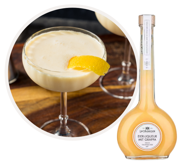 Eine Flasche Eierlikör mit Grappa neben einem gefüllten Cocktailglas, dekoriert mit einer Zitronenzeste.