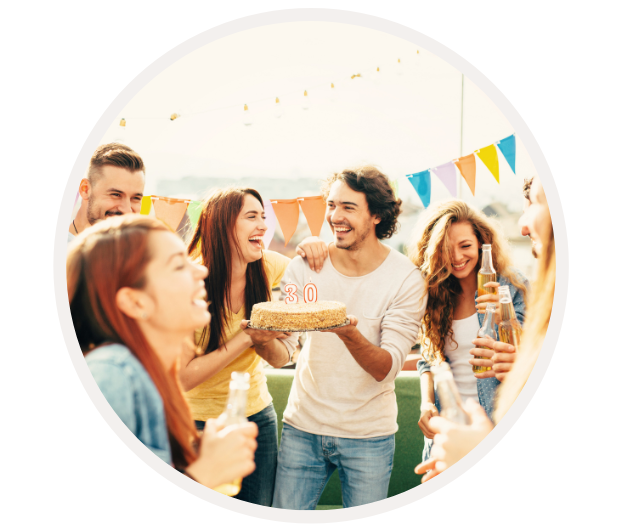 Eine Gruppe von Freunden feiert im Freien einen 30. Geburtstag mit einer Geburtstagstorte und Getränken.