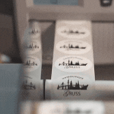 Nahaufnahme von Etiketten auf einem Drucker mit Stadtsilhouette und 'Mit freundlichen Grüßen'-Text.