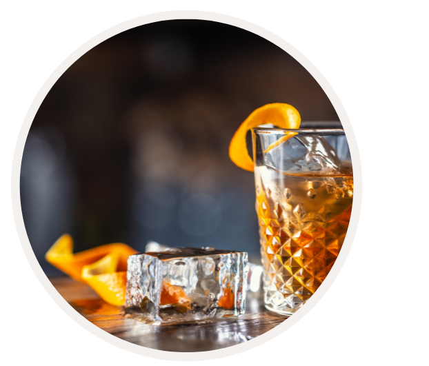 Ein Cocktail mit Orangenschale und großen Eiswürfeln auf einem Holztisch