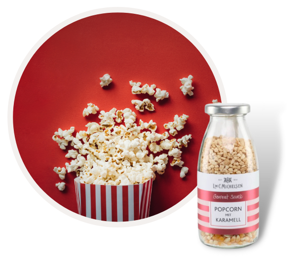 Gourmet-Popcorn mit Karamell in rot-weiß gestreiftem Becher auf rotem Hintergrund und Müsli-Glas mit Popcorn