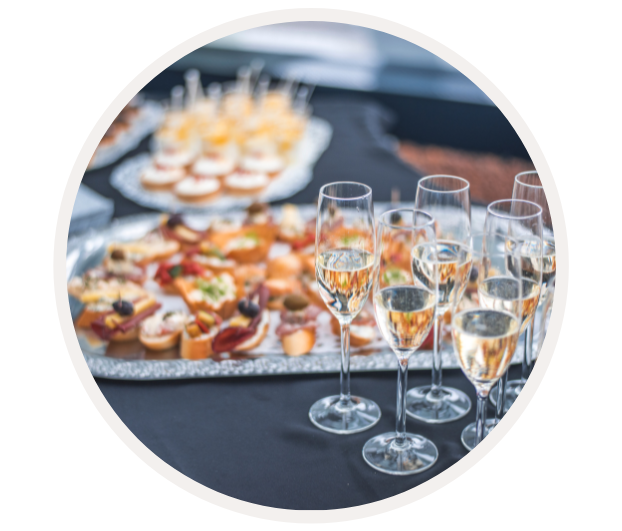 Mehrere gefüllte Sektgläser und dekorative Canapés auf einem Tisch, bereit für ein Event