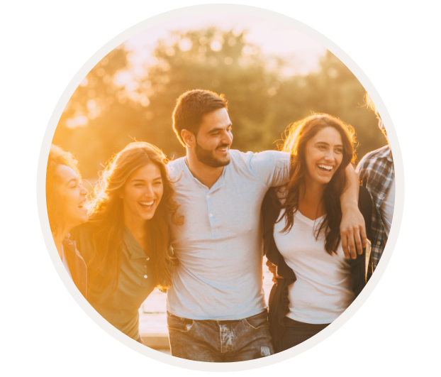 Gruppe von fröhlichen jungen Erwachsenen, die im Sonnenuntergang zusammenstehen und lachen