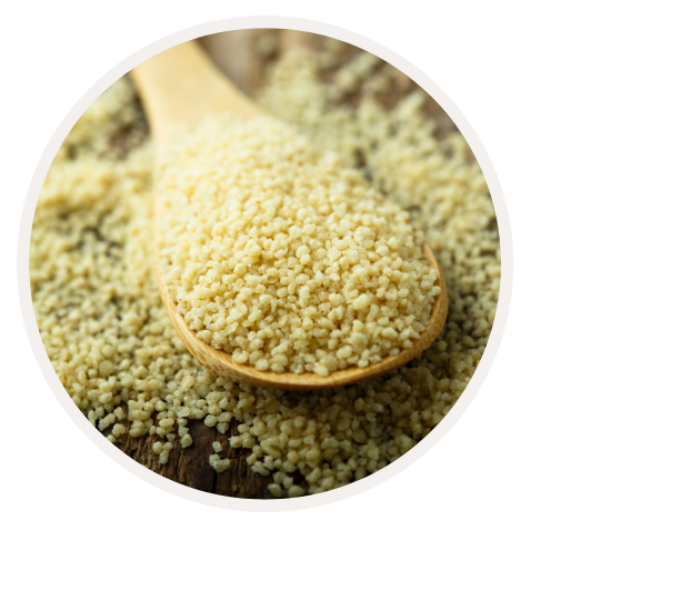 Nahaufnahme von rohem Couscous auf einem Holzlöffel, der auf einem Holztisch liegt