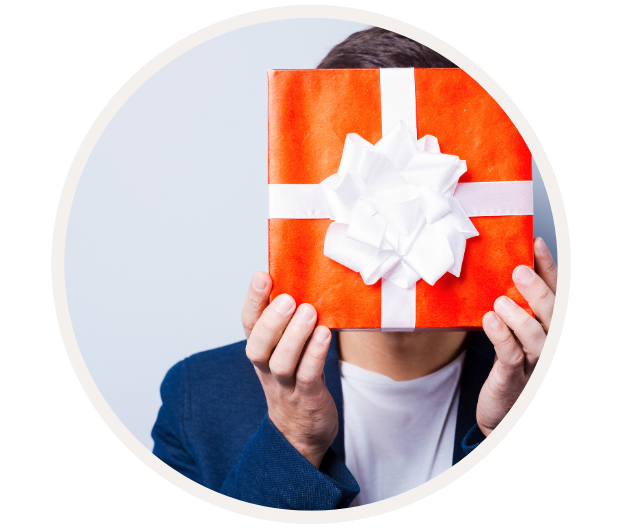 Person hält ein rotes Geschenk mit weißer Schleife vor dem Gesicht, Hintergrund neutral