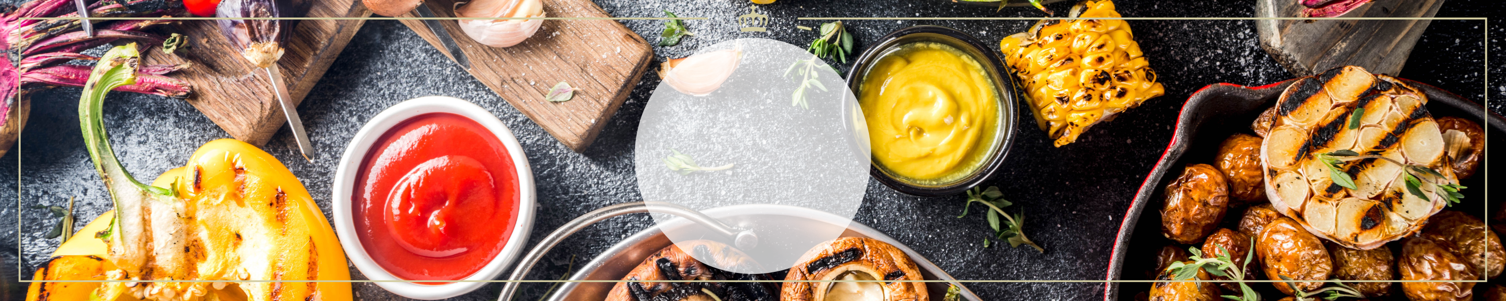 Eine Auswahl an Grillbeilagen wie gegrilltes Gemüse, Kartoffeln, Maiskolben, Knoblauch und Dips auf einem rustikalen Tisch.