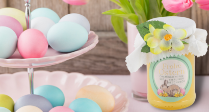 Bunte Ostereier auf einer Etagere neben einem Glas Honig mit Osterdekoration