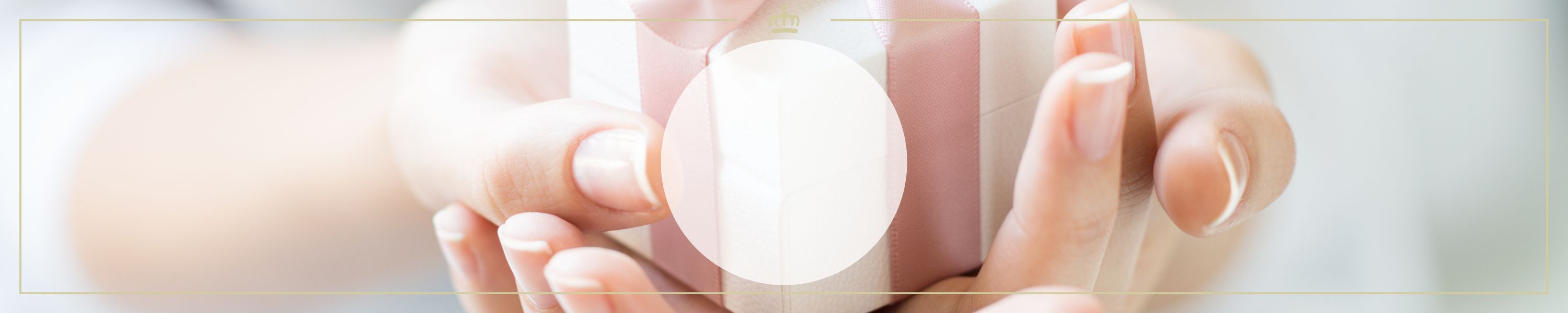 Nahaufnahme einer Geschenkbox mit rosa Schleife, gehalten von Händen vor unscharfem Hintergrund