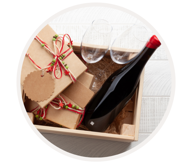 Holzkiste mit einer Flasche Rotwein, zwei Gläsern und mehreren Geschenkboxen auf einem weißen Hintergrund
