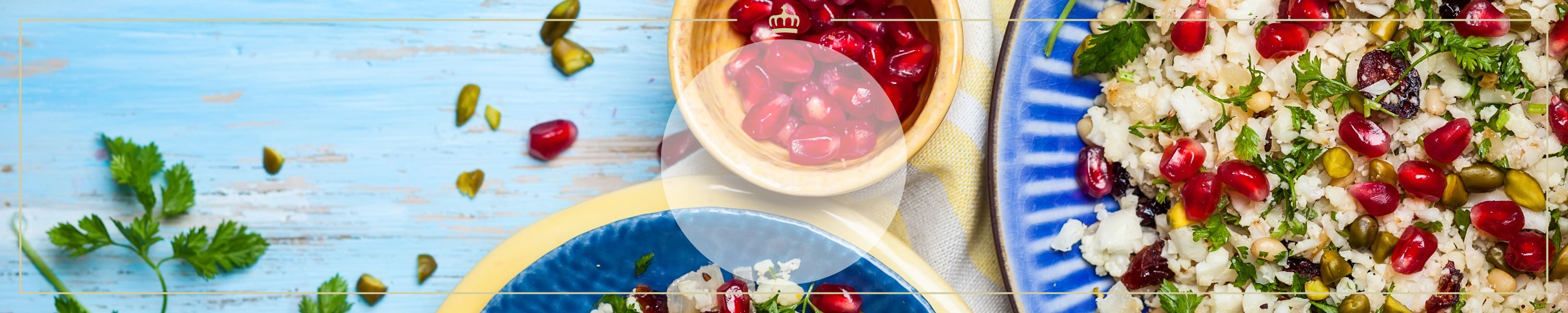 Bunter Salat aus Blumenkohl, Granatapfelkernen und Kräutern auf blauem Teller