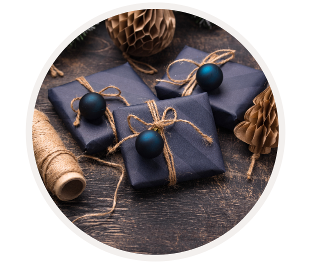 Drei elegant verpackte Geschenke mit blauer Deko auf dunklem Hintergrund, umgeben von Juteschnur und Papierdekoration.