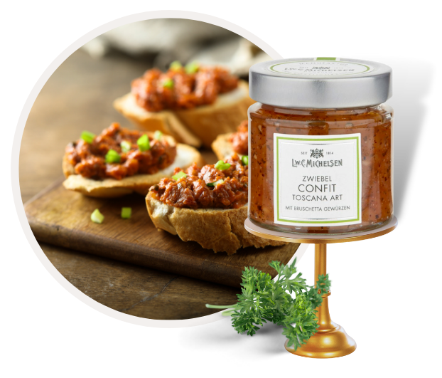 Ein Glas Zwiebel Confit Toscana Art mit Bruschetta Gewürzen neben Bruschetta-Häppchen auf einem Holzbrett