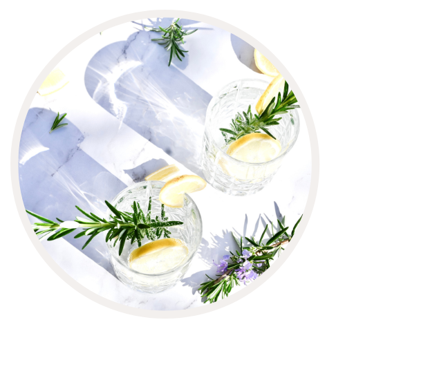 Zwei Gläser mit Zitronen-Rosmarin-Getränk auf Marmorunterlage, geschmückt mit Rosmarinzweigen
