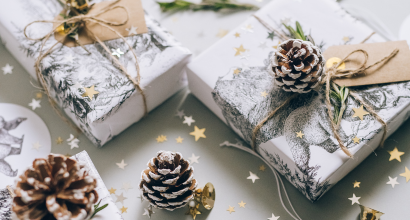 Weihnachtlich verpackte Geschenke mit Tannenzapfen, Sternkonfetti und natürlichen Verzierungen auf einem Tisch