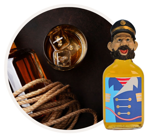 Eine bunte Flasche mit Matrosenabbildung steht neben einem gefüllten Whiskyglas und einem Seil auf dunklem Hintergrund.