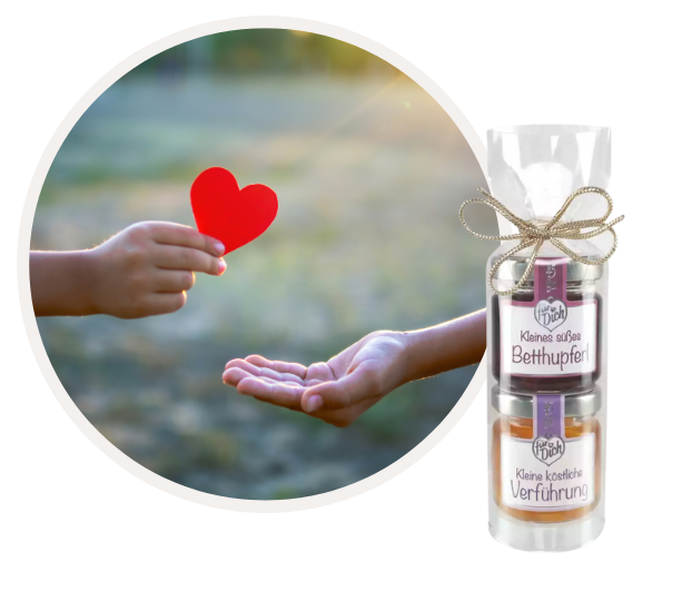 Hand überreicht rotes Herzsymbol neben Geschenkset mit einer Schleife gebunden.